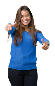 Young beautiful brunette woman wearing blue sweater over isolated background approving doing positive gesture with hand, thumbs up smiling and happy for success. Looking at the camera, winner gesture.