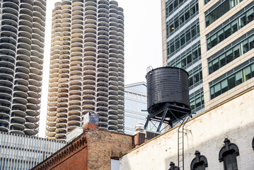 Water tank on the roof of an old brick building surrounded by modern skyscrapers in a downtown district