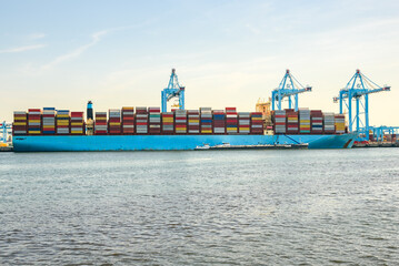 Large container ship moored to a container terminal at sunset