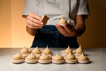 Female cook fastens the halves of macaroons smeared with cream