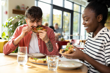 Young couple having pizza in a cafe and looking enjoyed