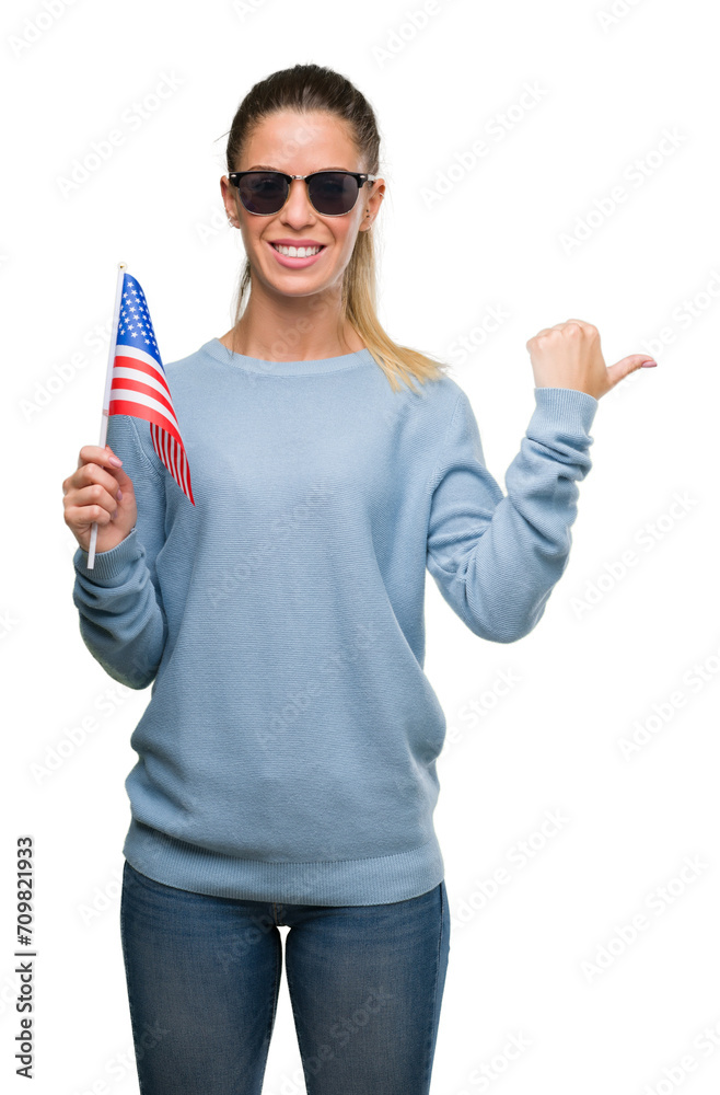 Sticker beautiful young woman holding usa flag pointing with hand and finger up with happy face smiling