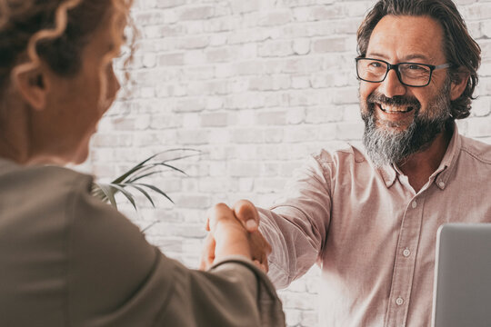 Couple Of Seller And Buyer Holding Hands To Sign An Agreement. Confident Professional Business Man Give Hand To Woman Client Sitting At The Desk In The Office. Concept Of Business Activity And People