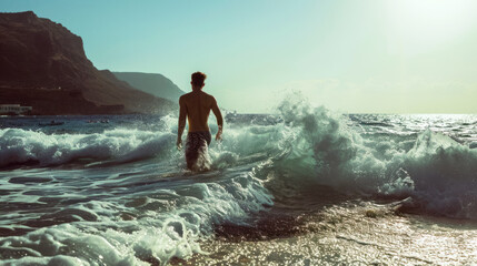 A young man enters the stormy sea to enjoy swimming, outdoor recreation, the sea as a symbol of struggle and mental decisions in life, enjoying freedom - obrazy, fototapety, plakaty