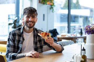 Smiling young man looking enjoyed while eating pizza