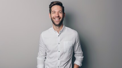 Man in formal attire, hands in his pockets, smiling at the camera against a gray backdrop.
