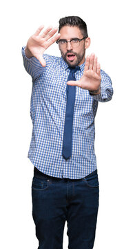 Young business man wearing glasses over isolated background Smiling doing frame using hands palms and fingers, camera perspective