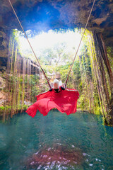 A beautiful young blonde girl wearing a long red dress swings on a swing - Ik-Kil Cenote - Lovely...