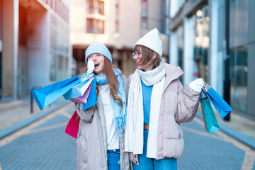 women girlfriends   with colorful shopping gift bags having a fun time together, talking and using...