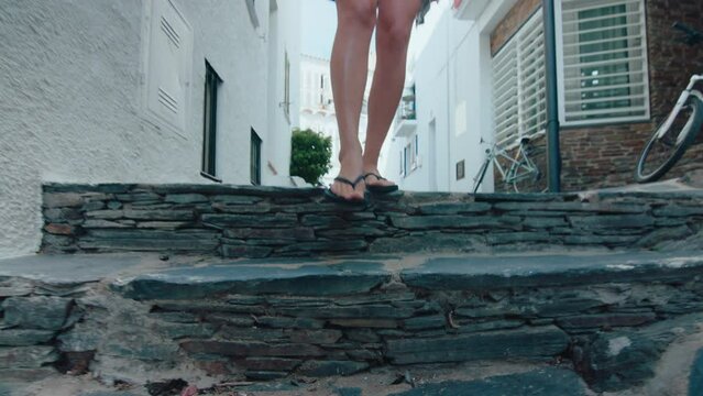 Female legs in flipflops walk on stone street . High quality 4k footage