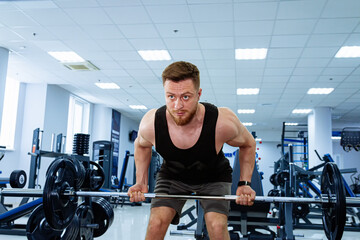 Man Performing Squat Exercise on Barbell in Gym. A man demonstrates proper squat form by squatting...