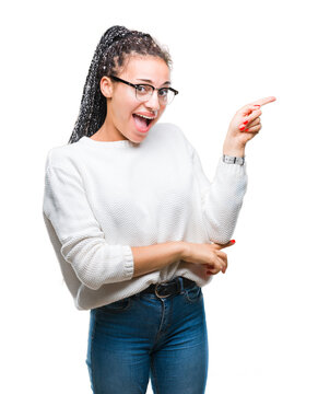 Young braided hair african american girl wearing glasses and sweater over isolated background with a big smile on face, pointing with hand and finger to the side looking at the camera.