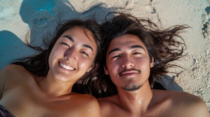 selfie portrait of an Asian heterosexual couple, laying on the sandy beach together sunbathing,