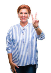 Atrractive senior caucasian redhead woman over isolated background smiling with happy face winking at the camera doing victory sign. Number two.