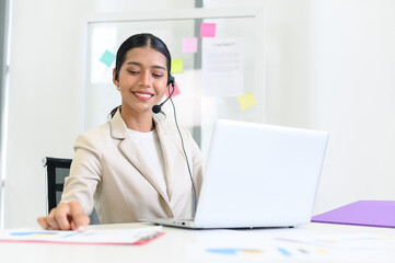Young beautiful friendly operator woman with headset working in a call center. customer service pay attention and talking to customers while using computer at office.