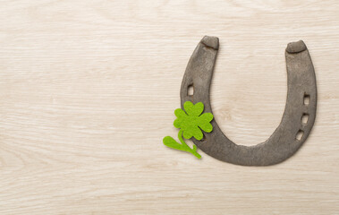 Metal horseshoe with clovers on wooden background, top view. St. Patricks day concept