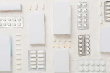 Different pills in blister packaging and boxes and on concrete background, top view