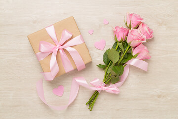 Fototapeta na wymiar Pink roses with hearts and gift box on wooden background, top view. Valentines day concept