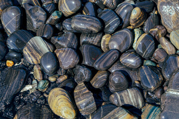 Background with black stones softly rounded. Pebble stones on the beach, Lipe Island, Stun, Thailand