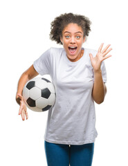 Young beautiful afro american holding soccer football ball over isolated background very happy and excited, winner expression celebrating victory screaming with big smile and raised hands