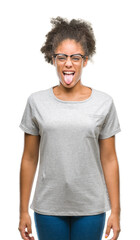 Fototapeta na wymiar Young afro american woman wearing glasses over isolated background sticking tongue out happy with funny expression. Emotion concept.