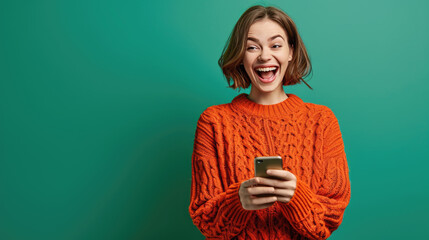 Fototapeta premium Young woman smiles joyfully while holding her smartphone against a colored background.