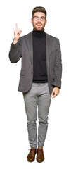 Young handsome business man wearing glasses pointing finger up with successful idea. Exited and happy. Number one.