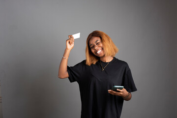 cheerful black lady using her phone and credit card