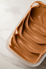 Brown cream for macaroons is beautifully distributed in a plastic container
