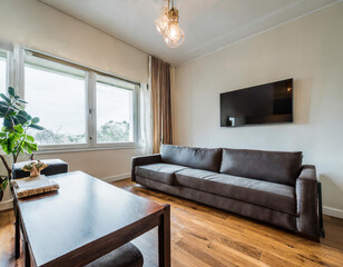 Elegant home living room interior with sophisticated seating and a polished wooden table. A mockup wall allows for personalization and artistic expression.