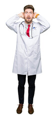 Fototapeta premium Young handsome doctor man wearing medical coat Crazy and scared with hands on head, afraid and surprised of shock with open mouth