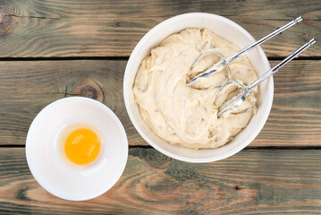 Dough from the mixer attachment and the egg yolk separated from the white for preparing baked goods.