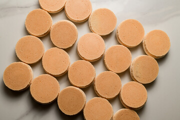 Freshly baked halves of pink macaroons lie on a table