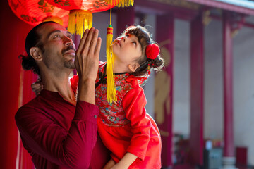 Happy father and daughter in traditional Chinese costumes enjoying a tour of the red lanterns in the shrine, Chinese New Year holiday