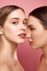 Bare-faced brilliance. Girls radiate beauty in unity. Close up of two pretty ladies with bare shoulders posing against pink studio background. Concept of health, self care, cosmetic products, make-up.