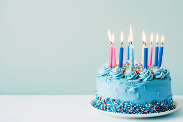 blue cake on a stand with lit candles on a blue background