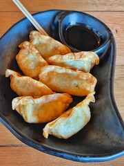deep fried Gyoza or Japanese dumpling stuffed minced pork dipping shoyu sauce on plate