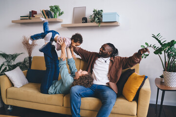 Happy multiracial family having fun together with stretched hands on sofa at home