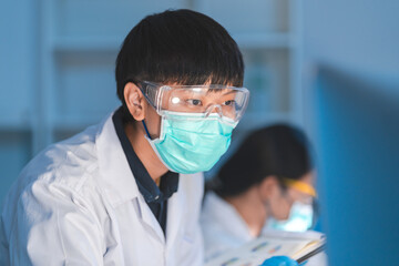 A Specialist and professional female scientists or researcher working concentration and serious with biology experiment data and examining online document result on computer late night in laboratory.