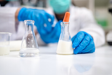 Close up of scientist or nutritionist dripping a sample of milk, fat or glucose in a test tube or beaker in laboratory, Expertise is working on lactose, protein experiment analysis or testing quality.
