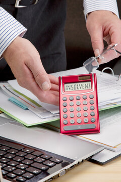 Schuldnerberater am Schreibtisch mit einem Taschenrechner, der im Display das Wort "Insolvenz" anzeigt