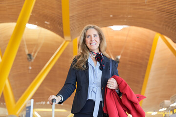 portrait of a middle aged business woman with travel luggage at the station