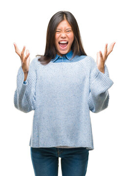 Young asian woman wearing winter sweater over isolated background celebrating crazy and amazed for success with arms raised and open eyes screaming excited. Winner concept