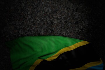 nice dark picture of Tanzania flag with big folds on dark asphalt with empty place for your text - any occasion flag 3d illustration..
