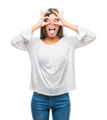 Young asian woman over isolated background doing ok gesture like binoculars sticking tongue out, eyes looking through fingers. Crazy expression.