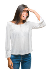 Fototapeta premium Young asian woman over isolated background very happy and smiling looking far away with hand over head. Searching concept.