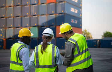 Group of engineers working with laptop in the container yard. This is a freight transportation and distribution warehouse.