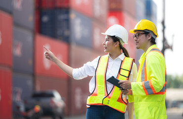 Portrait of Asian woman engineer and worker working with co-worker at overseas shipping container yard.