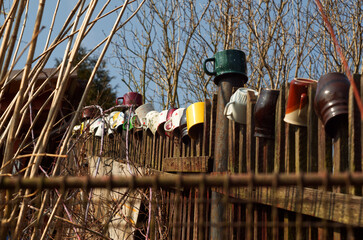 multicolored mugs arranged on a weathered and rustic wooden fence