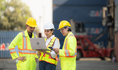 Group of engineers working with laptop in the container yard. This is a freight transportation and distribution warehouse.